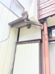 三重県桑名市西別所 1階軒下の外壁入隅に営巣したコガタスズメバチの巣（直径約25cm・巣の半分が壁に密着）